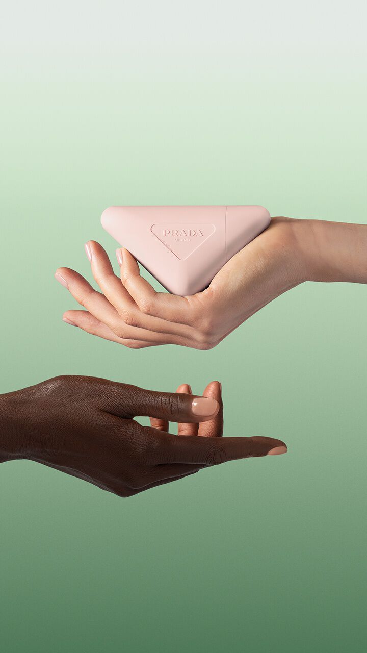 Prada Paradoxe Hand Cream Key Visual with Light and Dark skinned hands on a green background